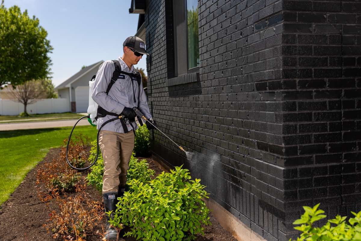 EntoLogic technician applying perimeter pest prevention treatment